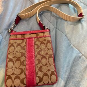 Coach signature canvas crossbody bag with a pink leather trim and strap accents.
